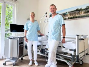 Stationsleitung Jacqueline Peters und ein Pfleger stehen vor einem neuen Patientenbett in einem Patientenzimmer der Klinik Sanssouci.